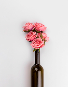 Rosa Blume in einer Weinflasche – Symbol für den Frühlingsanfang im Wein-Markt Jansen
